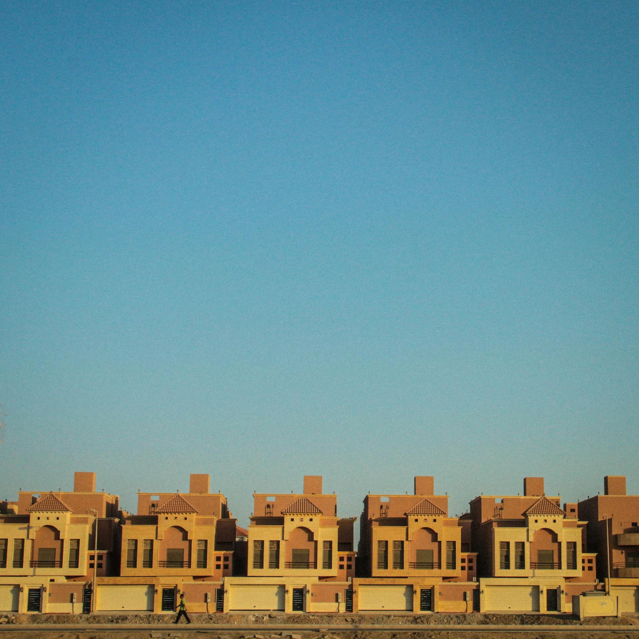 A picturesque row of terraced houses set against a bright clear blue sky, showcasing modern architecture.