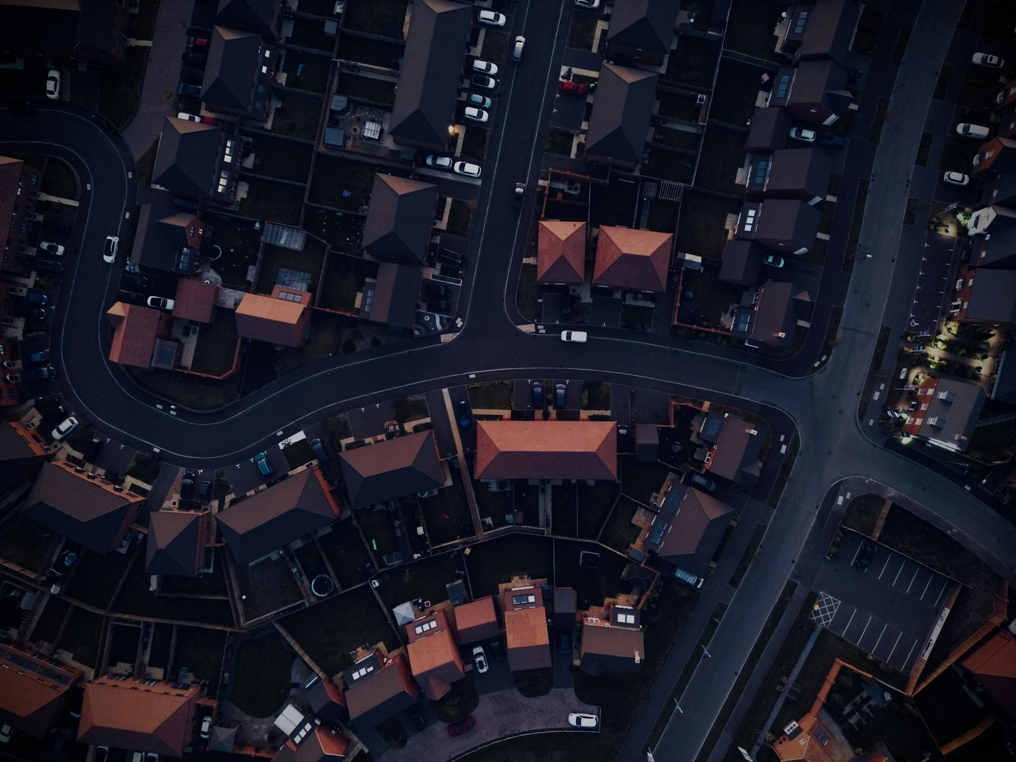 Aerial shot of suburban neighborhood streets and houses during twilight.