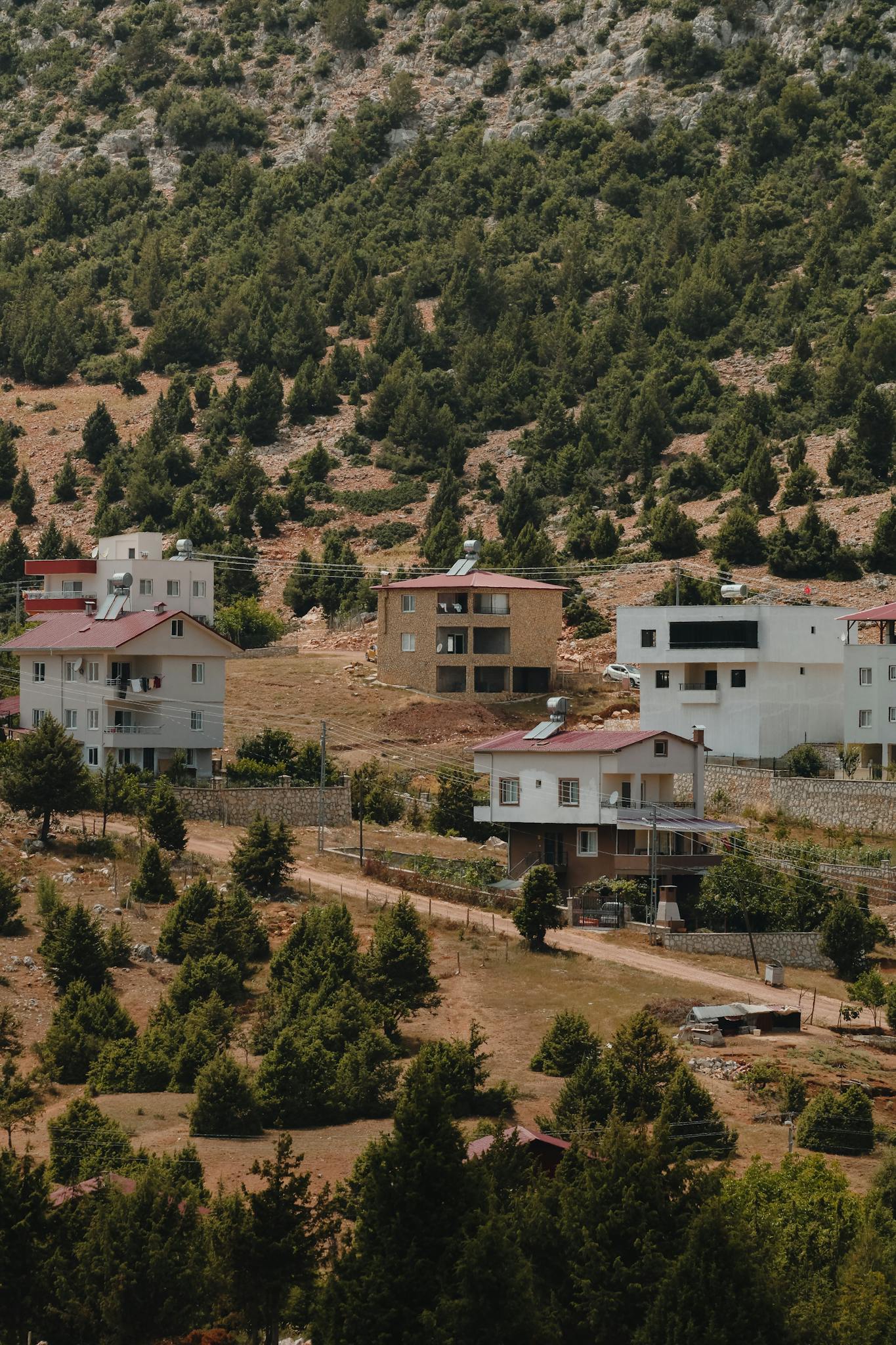 Aerial view of a rural residential area surrounded by lush greenery and hills.