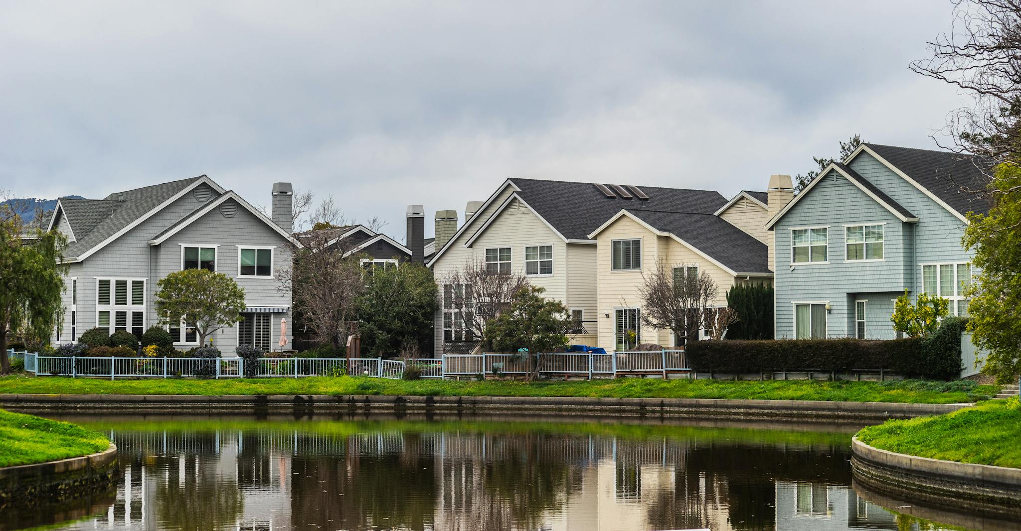 Beautiful suburban houses reflecting in a peaceful riverside setting with lush greenery.